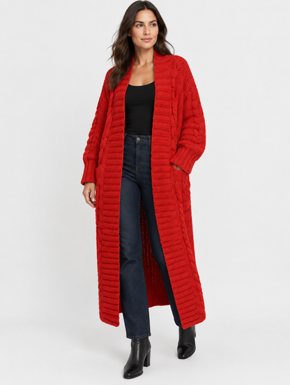 Woman wearing the Maren red chunky cable-knit maxi cardigan over a black tank and dark jeans